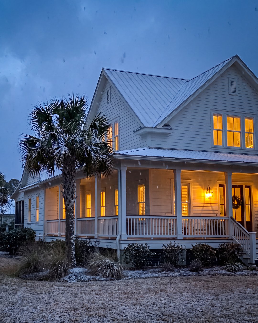 A Southern brick home at dusk during a freeze, frost on the lawn and warm light in the windows